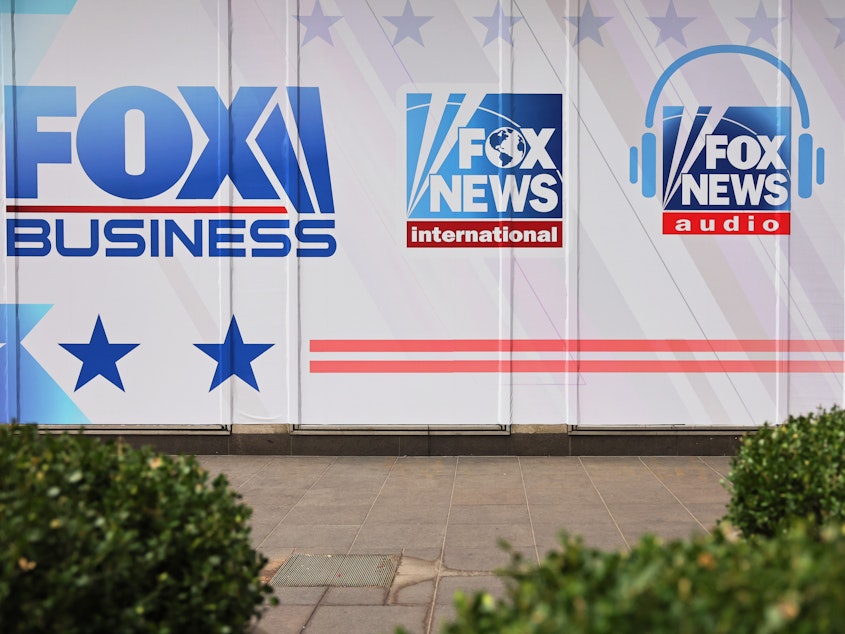 caption: Fox News and its parent company are being sued for defamation over false claims of election fraud following the 2020 election. Above, logos for Fox News Media's growing portfolio of brands adorn its corporate headquarters in New York City.