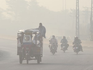caption: Commuters make their way down a smoggy road in Lahore, Pakistan in 2022. Extreme heat waves make air pollution, like smog, worse.