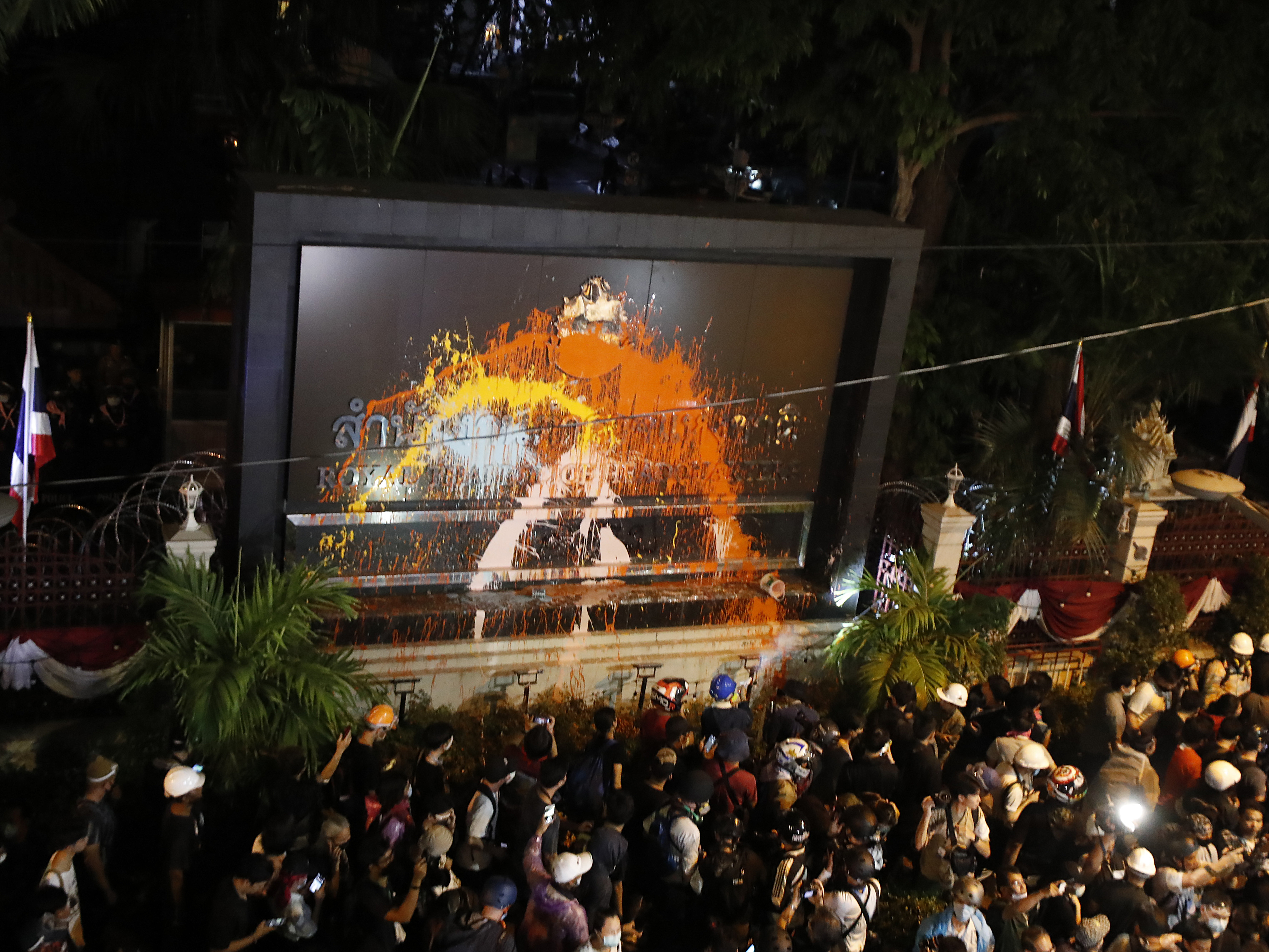 caption: Pro-democracy protesters splash colored paint on the police headquarters sign in Bangkok, Thailand, on Wednesday.