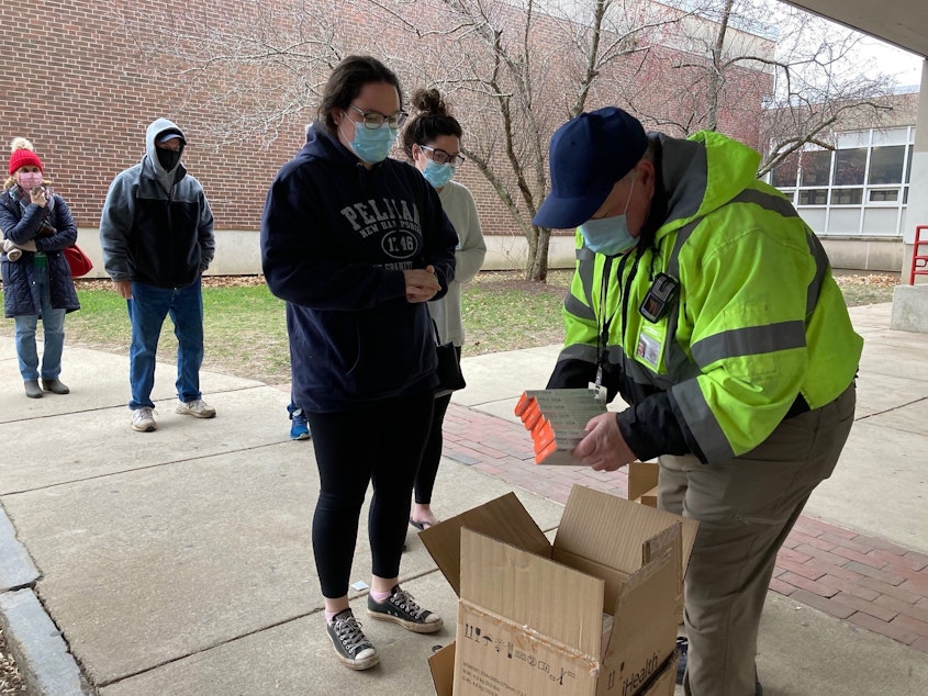 caption: Don Murphy hands out free rapid COVID tests outside of Robinson Middle School in Lowell, Massachusetts.