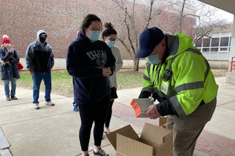 caption: Don Murphy hands out free rapid COVID tests outside of Robinson Middle School in Lowell, Massachusetts.