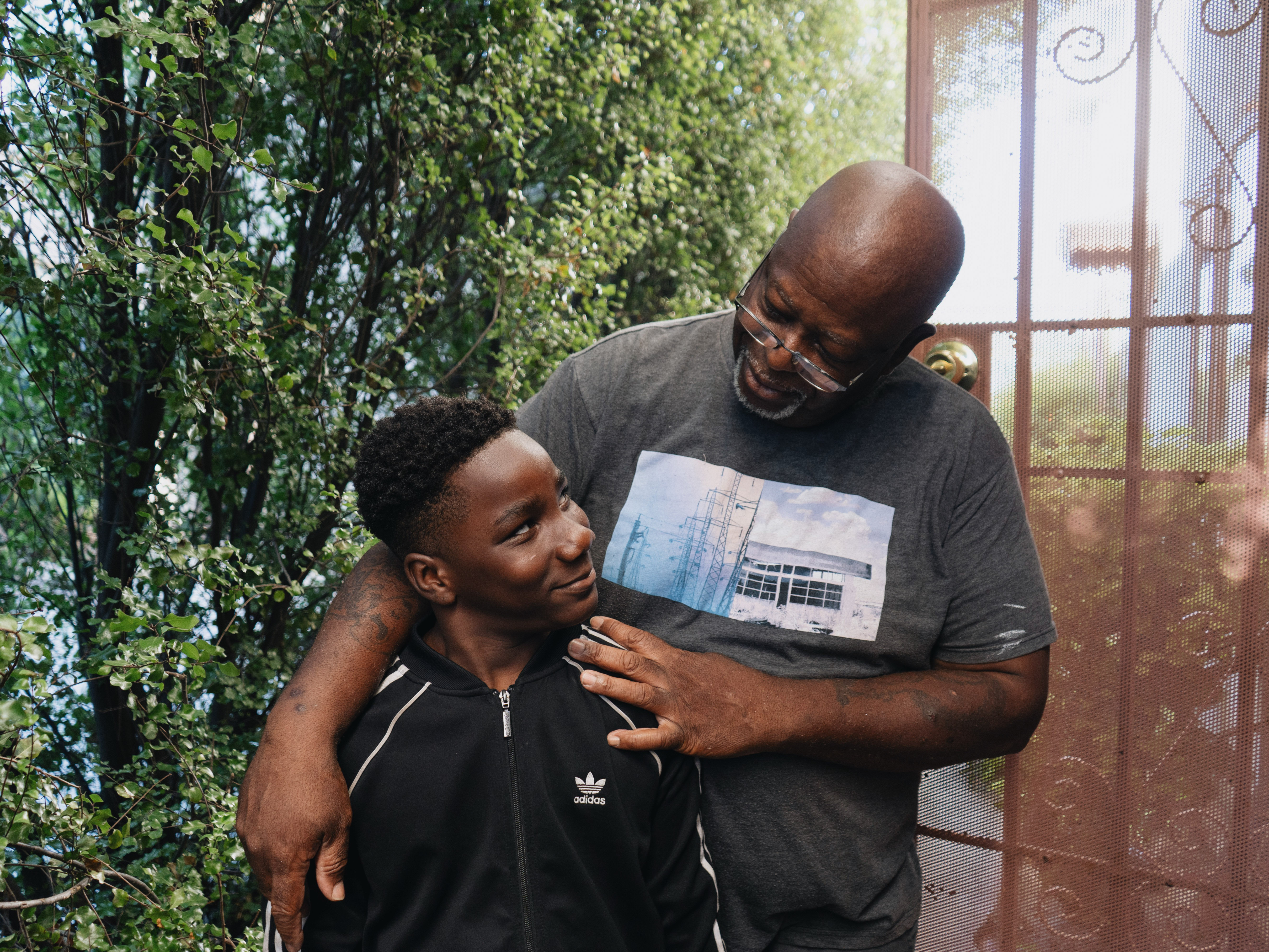 caption: Ziare Gearring (left) and his grandfather Ricky Brown pose for a portrait outside of their home in Los Angeles. The 65-year-old retired handyman had already been struggling, and taking in three grandsons after his ex-wife's sudden death has put him thousands of dollars behind on rent and utilities.