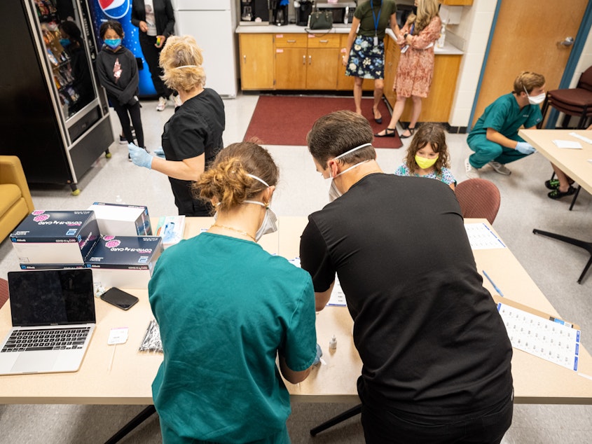 caption: Nurses work at a COVID-19 testing day for students and school faculty at Brandeis Elementary School on in Louisville, Ky.