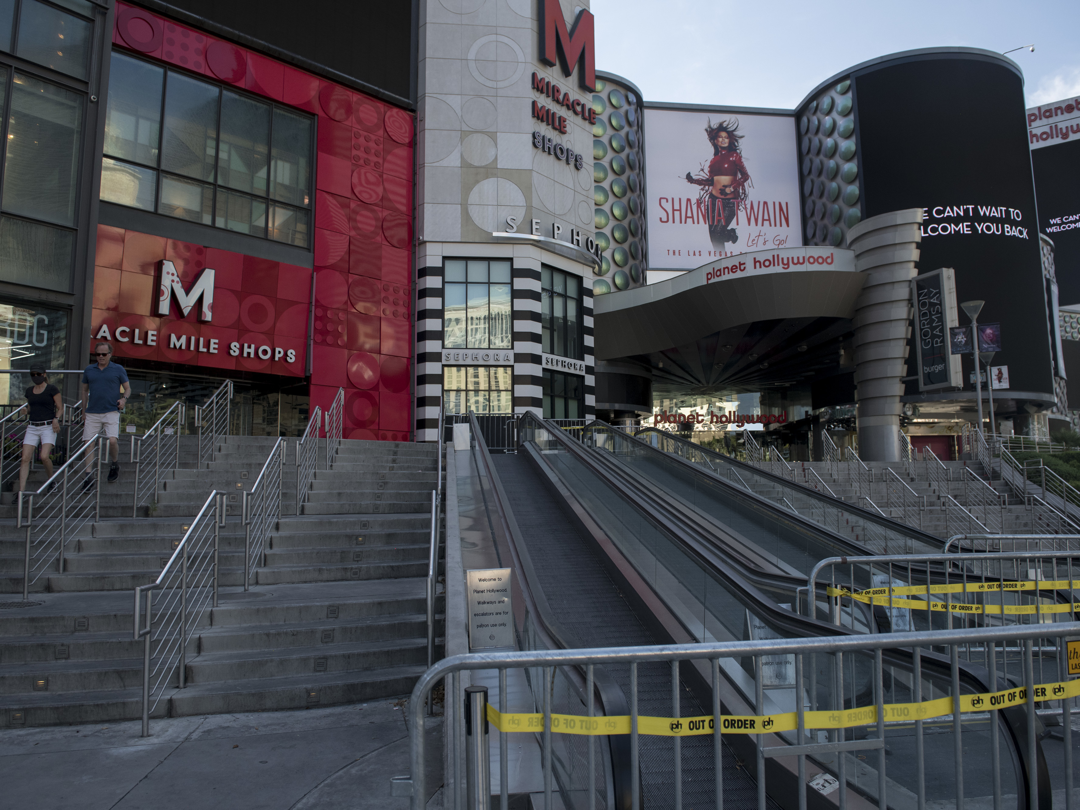 caption: People walk near closed shops on a quiet Las Vegas Strip amid the coronavirus pandemic on May 8.