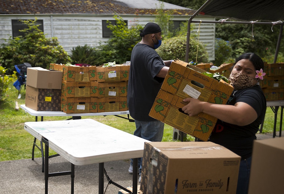 caption: Louise Chan Kau moves boxes of fresh produce, meat and dairy at a free food distribution site led by the Pacific Islander Community Association of Washington on Thursday, July 10, 2020, along Military Road South in Kent. 