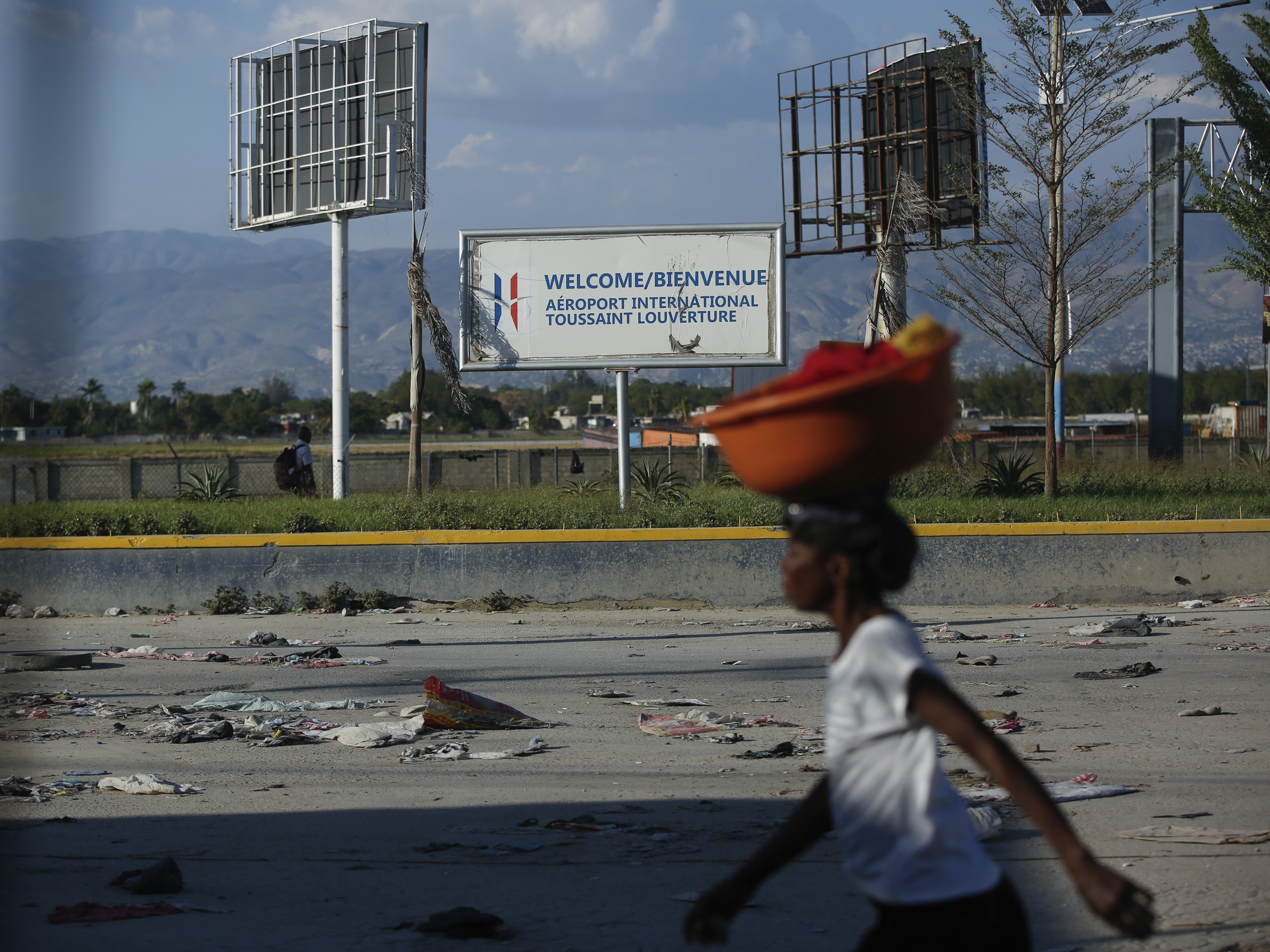 caption: A pedestrian walks past the international airport in Port-au-Prince, Haiti, Monday. Gang members exchanged gunfire with police and soldiers around the airport in the latest of a series of attacks on government sites.