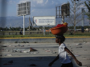caption: A pedestrian walks past the international airport in Port-au-Prince, Haiti, Monday. Gang members exchanged gunfire with police and soldiers around the airport in the latest of a series of attacks on government sites.