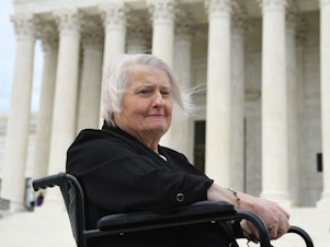 caption: Transgender activist Aimee Stephens sits in her wheelchair outside the Supreme Court on Oct. 8, 2019, as the court holds oral arguments in cases dealing with workplace discrimination based on sexual orientation.