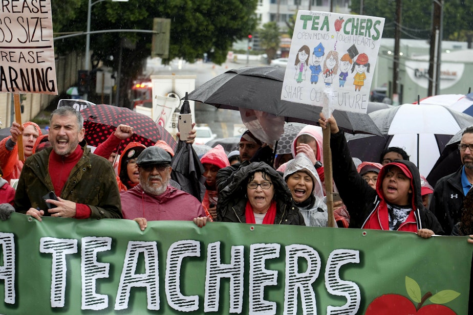 caption: Thousands of teachers and supporters hold signs in the rain during a rally Monday, Jan. 14, 2019, in Los Angeles. (Ringo H.W. Chiu/AP)