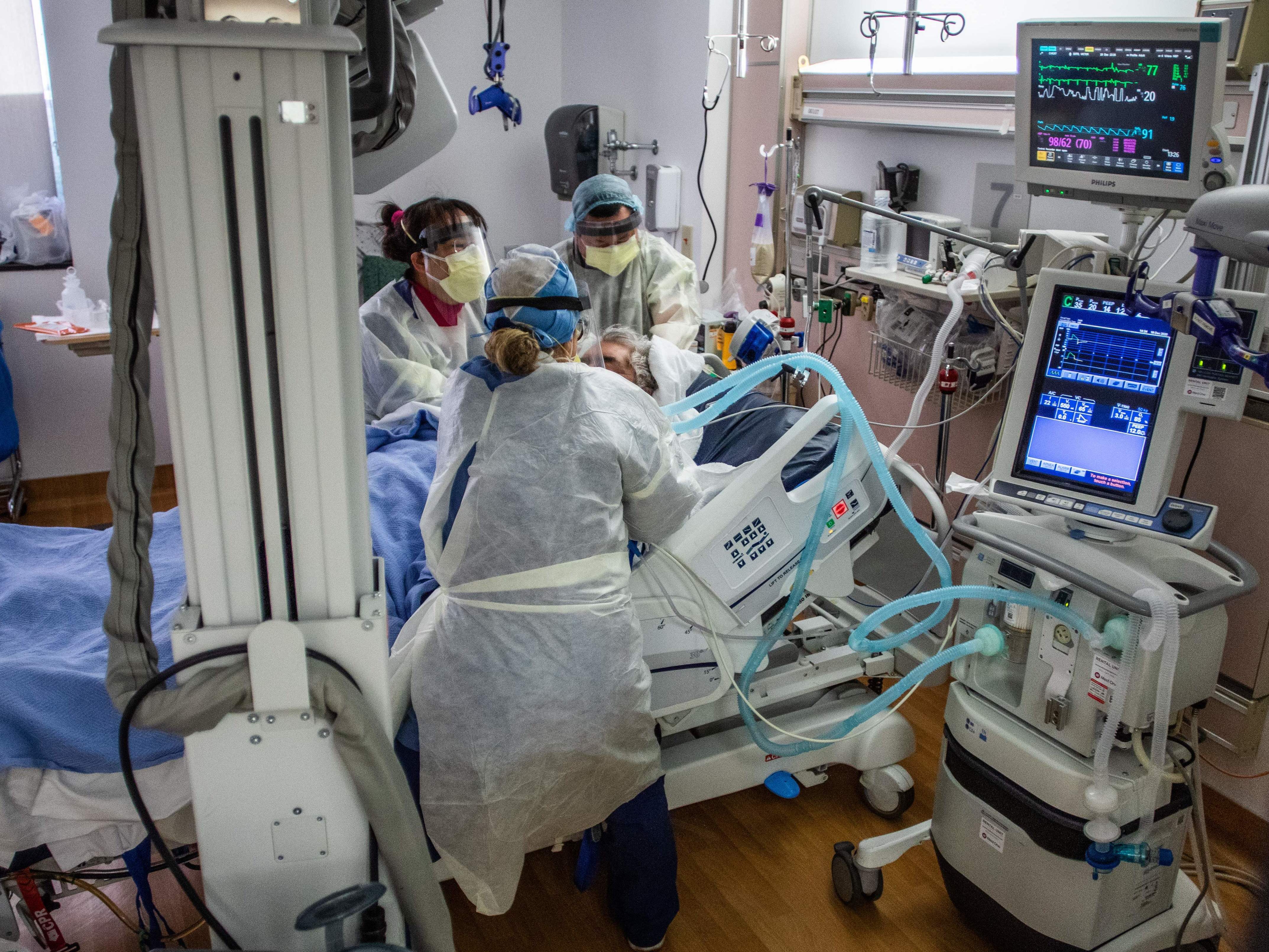 caption: Physicians and nurses wear personal protective equipment while they attend to a COVID-19 patient in the ICU at Providence Cedars-Sinai Tarzana Medical Center in Tarzana, Calif. on December 18, 2020.