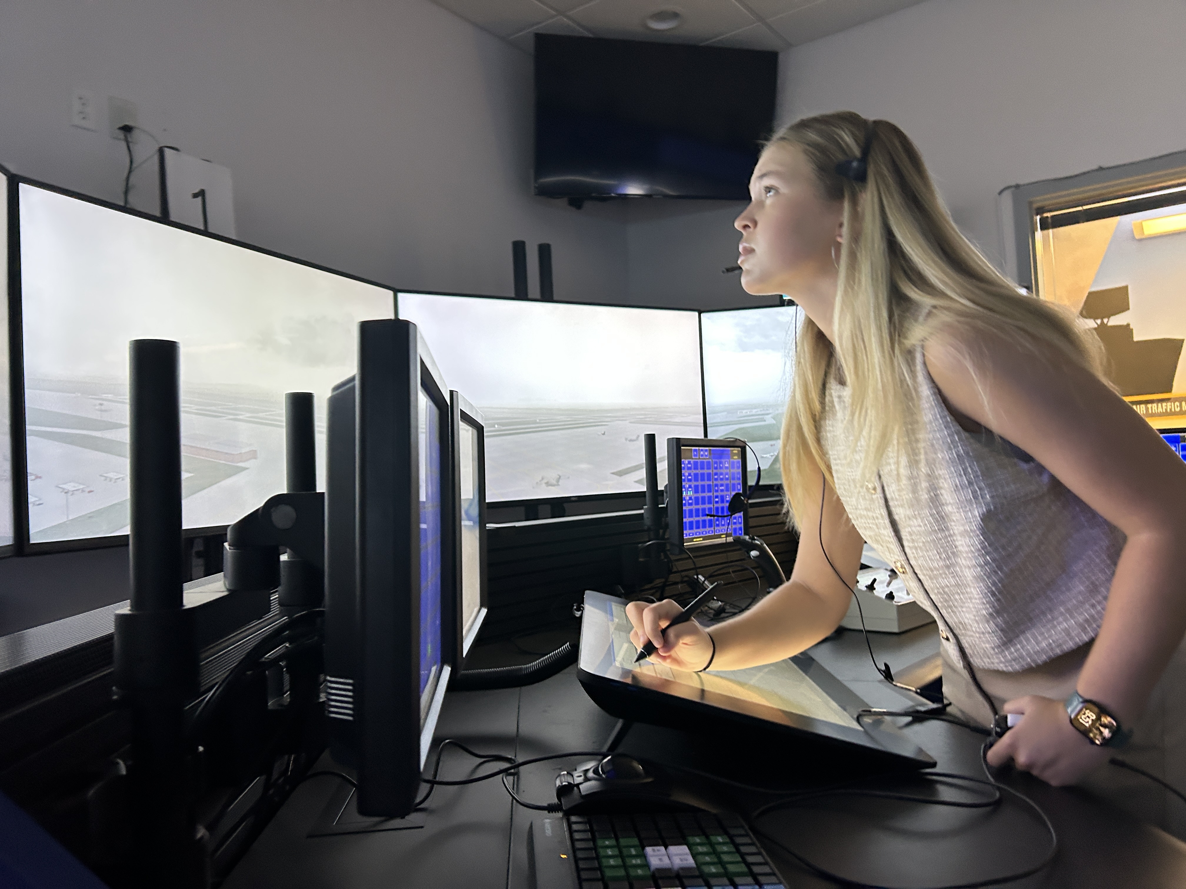 caption: Hailee Williamson stands behind the controls of an air traffic control simulator at Embry-Riddle Aeronautical University in Daytona Beach, Fla.