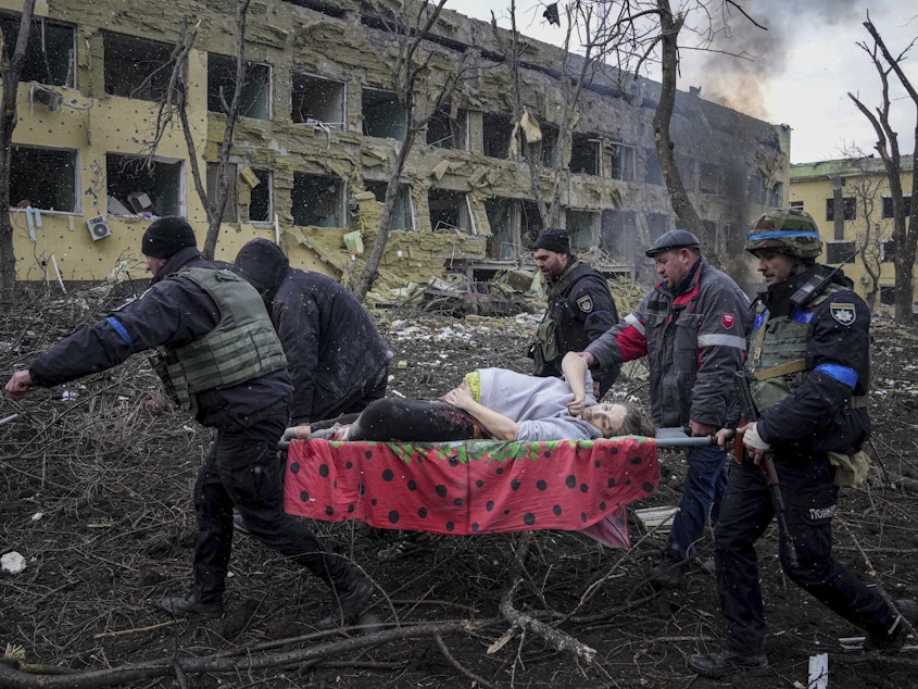 caption: First responders and volunteers carry an injured pregnant woman from a maternity hospital that was damaged by shelling in Mariupol, Ukraine, on Wednesday. The woman and her baby have since died.