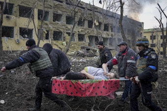 caption: First responders and volunteers carry an injured pregnant woman from a maternity hospital that was damaged by shelling in Mariupol, Ukraine, on Wednesday. The woman and her baby have since died.
