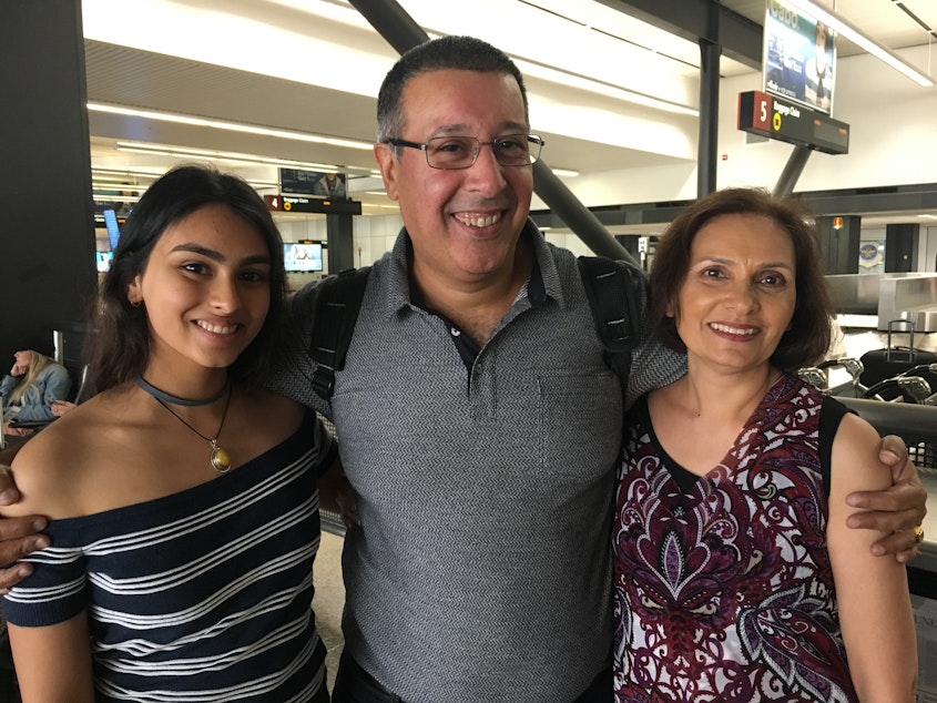 caption: Irfan Fazl, center, a dual citizen of the UK and Kenya, reunites with friends at Sea-Tac Airport after his flight from London. He's Muslim and his friends worried the travel ban might cause problems.