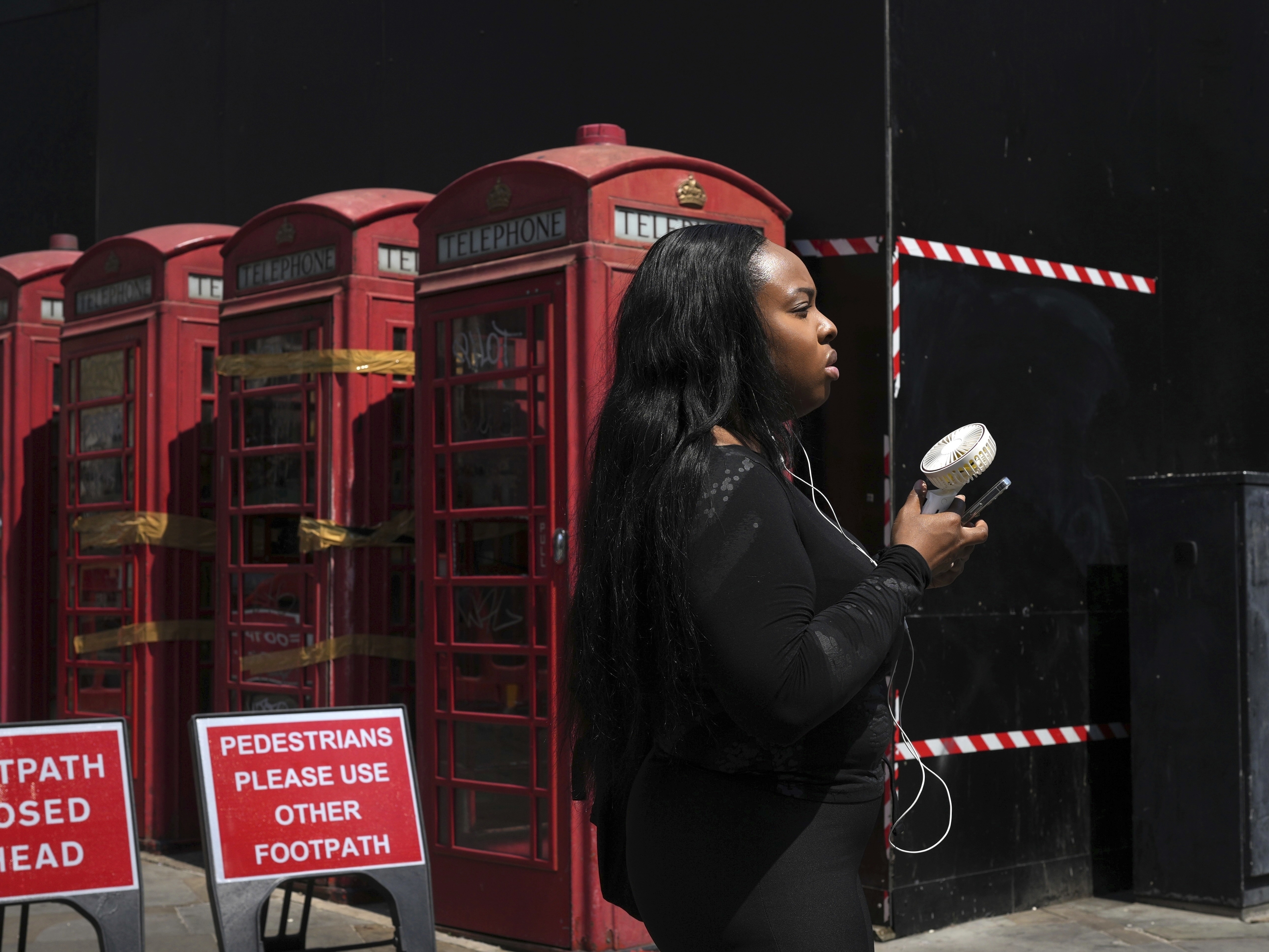 caption: A woman cools herself with a fan during a hot day in London on June 26, 2024. June 2024 was the hottest June on record, according to Europe's Copernicus climate service.