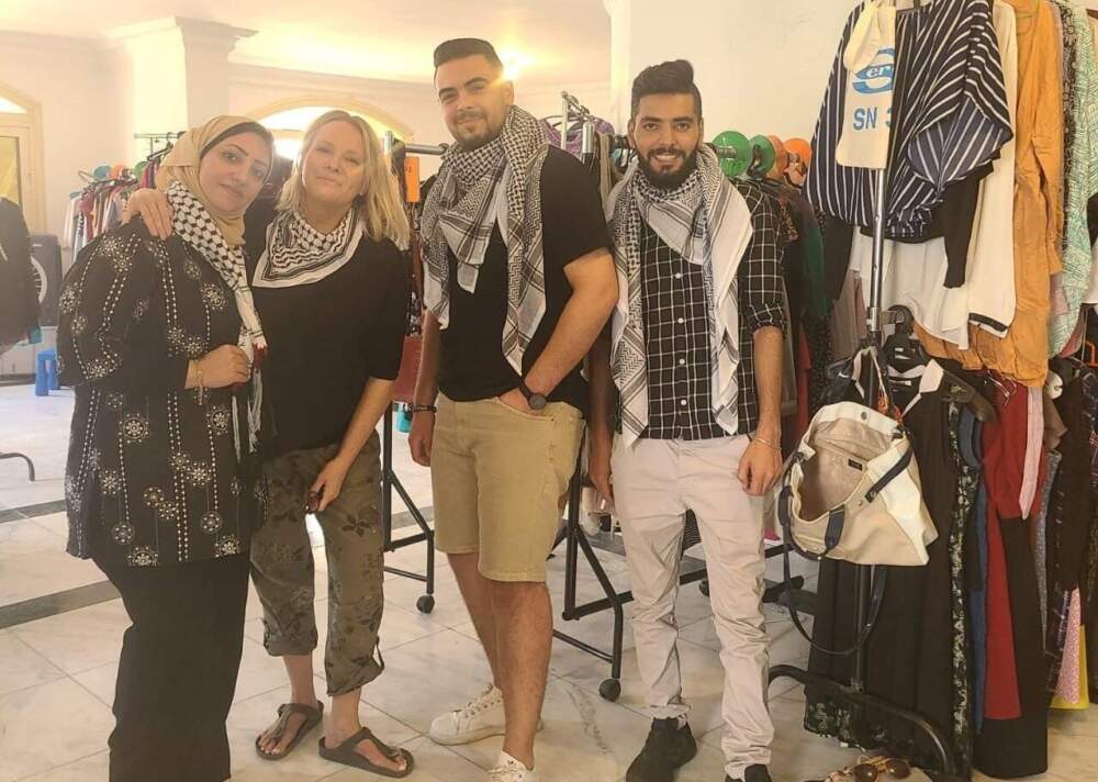 caption: Stephanie Hooper (second from left) is pictured with Palestinian volunteers helping out at a free clothing boutique she helped put together in Cairo for new arrivals who fled the war in Gaza. (Courtesy)