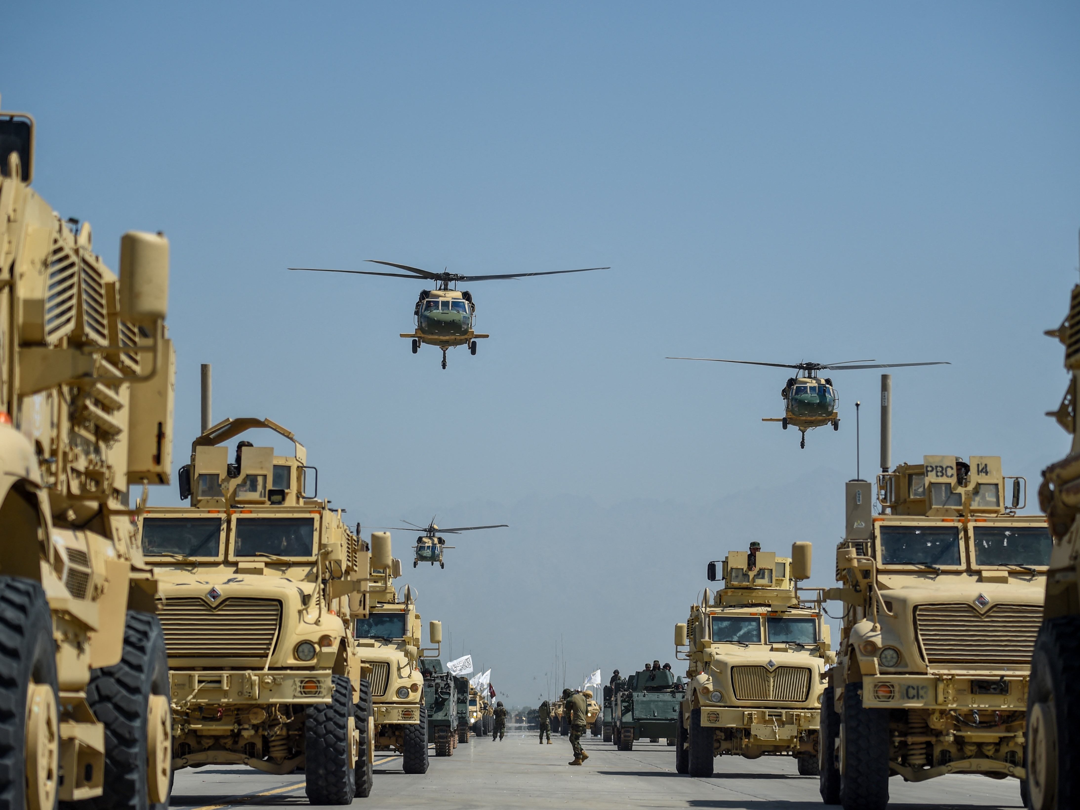 caption: In this file photo from 2024, Taliban military helicopters fly to celebrate the third anniversary of Taliban's takeover of Afghanistan, at the Bagram Air Base, in Bagram, Parwan province on August 14, 2024. President Trump banned the arrival of Afghan nationals to the U.S. with exceptions for those who have special immigrant visas.