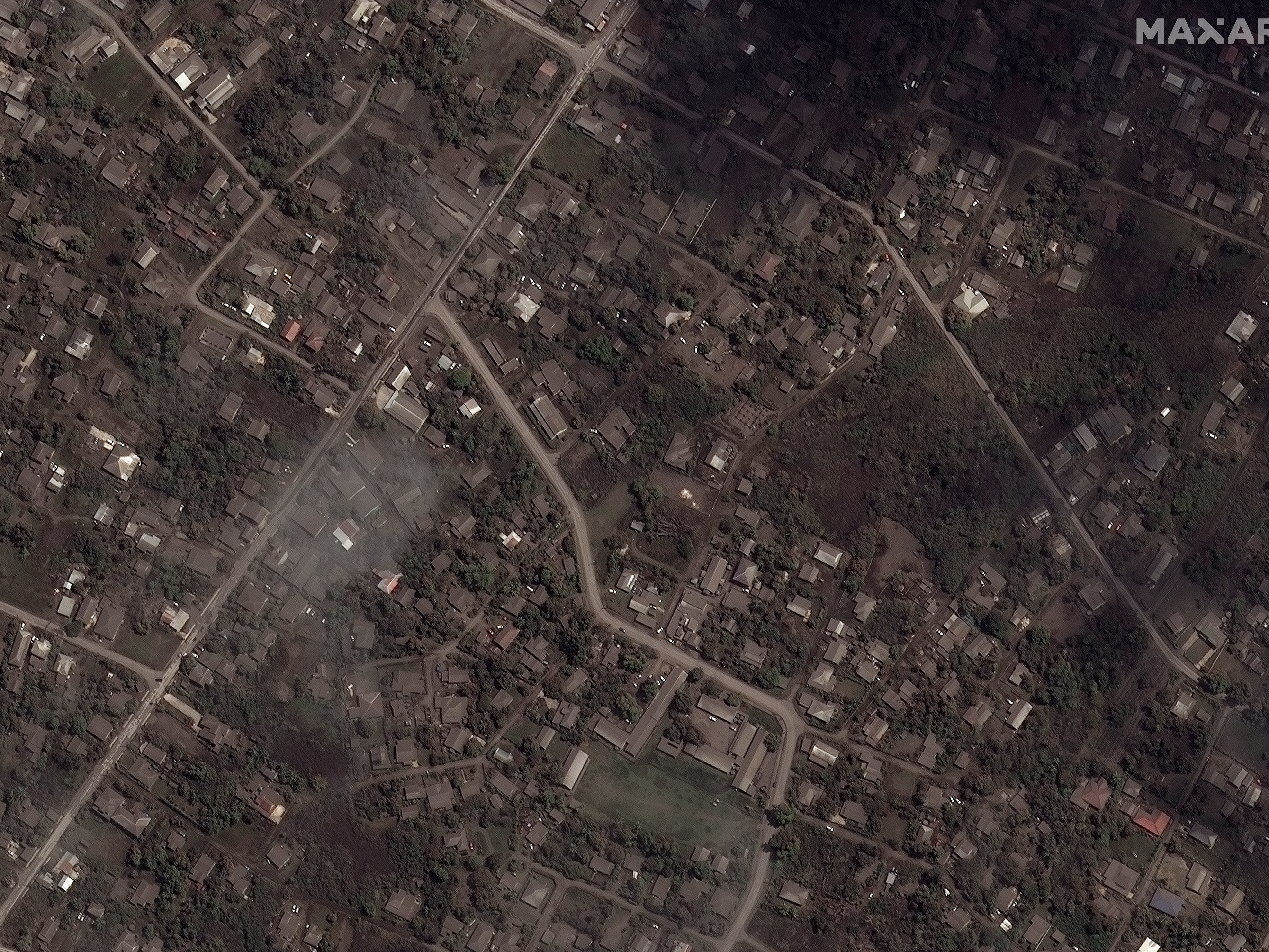 caption: This satellite image provided shows ash covered homes and buildings in Tonga Tuesday, Jan. 18, 2022 days after a huge undersea volcanic eruption.
