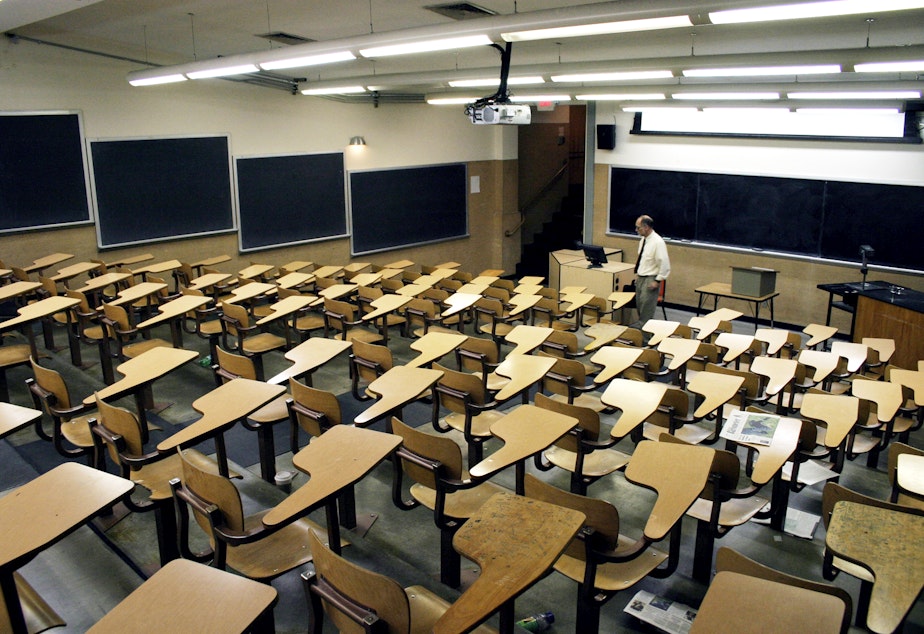 caption: Professor stands in front of an empty classroom