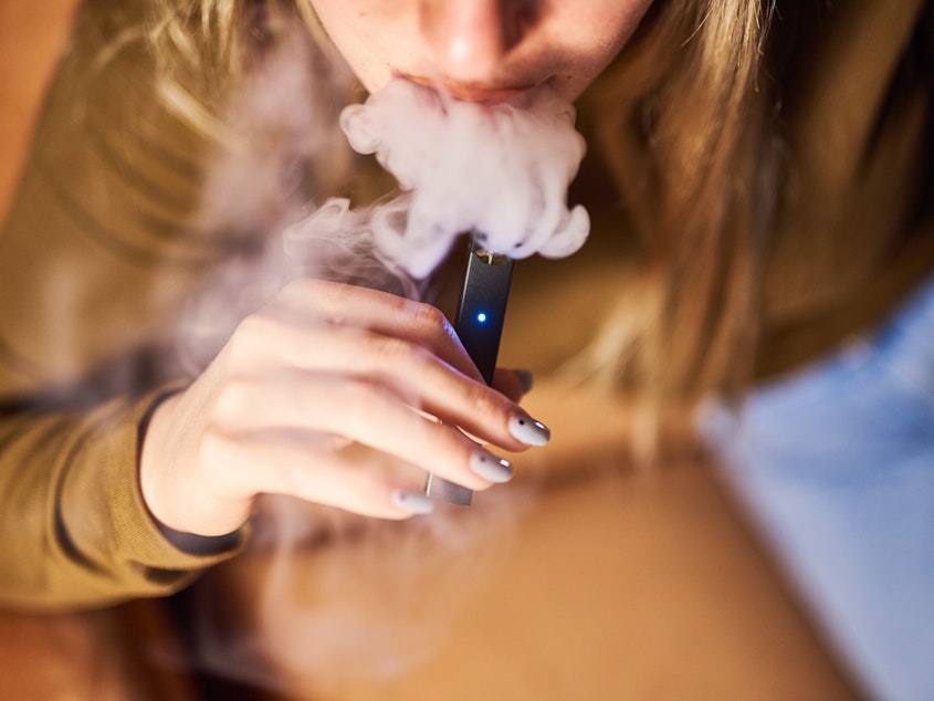 caption: A person smokes a Juul Labs Inc. e-cigarette in a photograph taken in New York, last year.