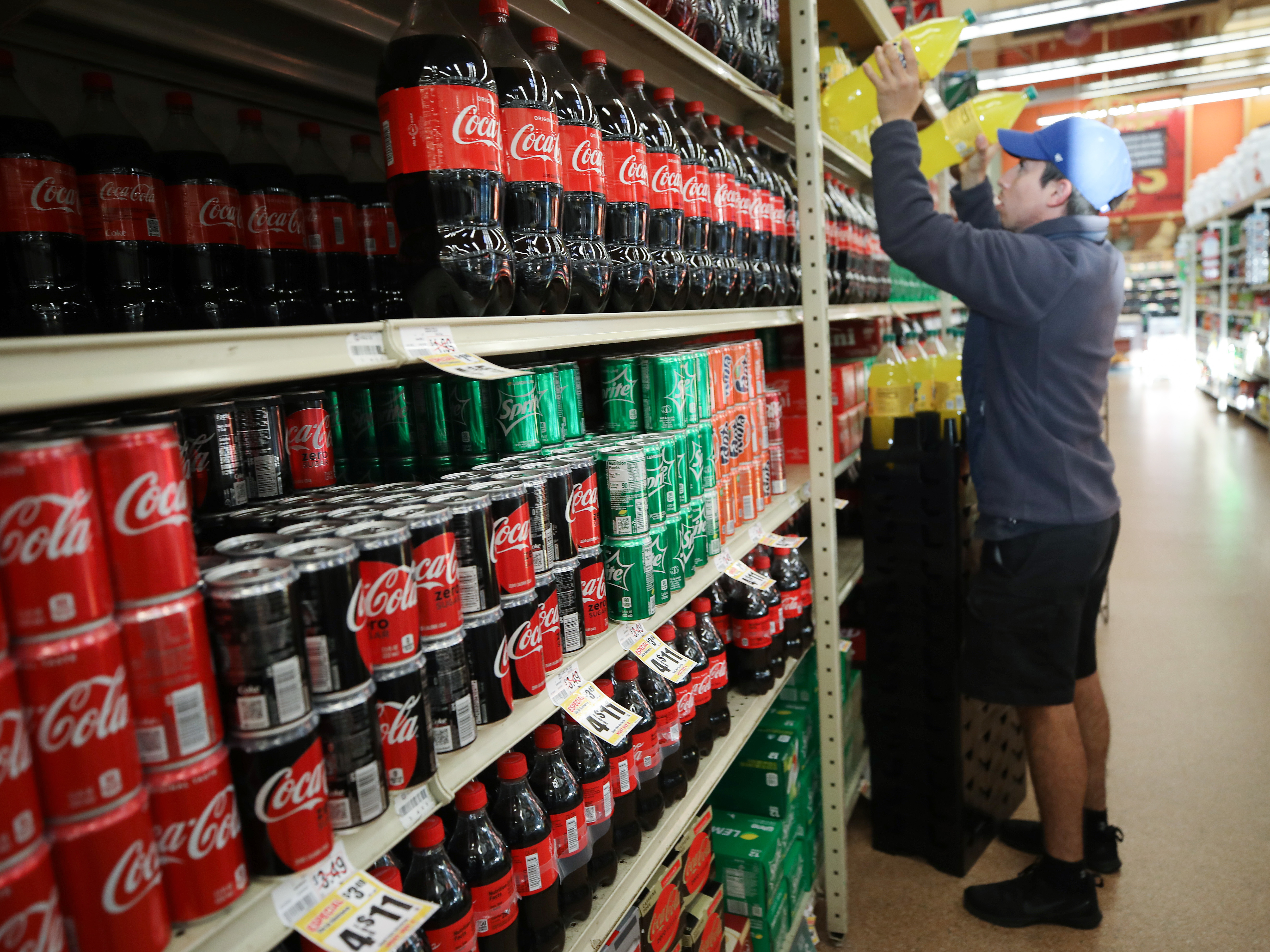 caption: A worker restocks sodas at a Hispanic specialty supermarket in Los Angeles on March 19. Nationally, sales of soft drinks were up 43% that week, compared to the same week in 2019.