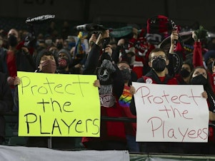 caption: Portland Thorns fans hold signs in October 2021 during the first half of the team's National Women's Soccer League soccer match against the Houston Dash in Portland, Ore.