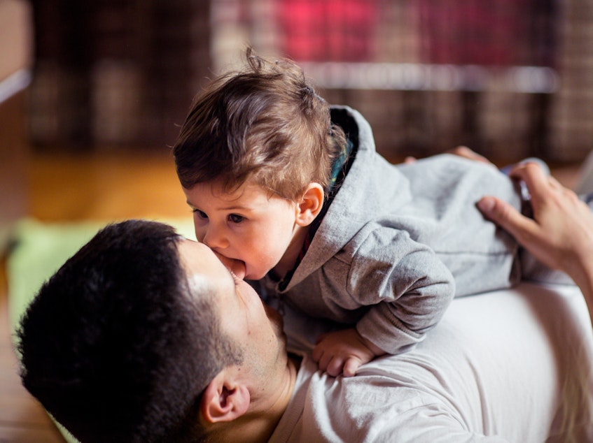 caption: This stock image shows a baby and father playing at home. New research finds that babies judge the relationship between two people by whether or not they willingly share saliva.