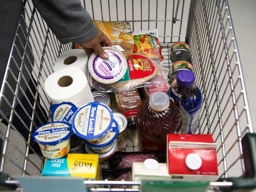 caption: A food pantry client adds a carton of yogurt to her cart at the food pantry at Jewish Family Services in Denver, Colo.