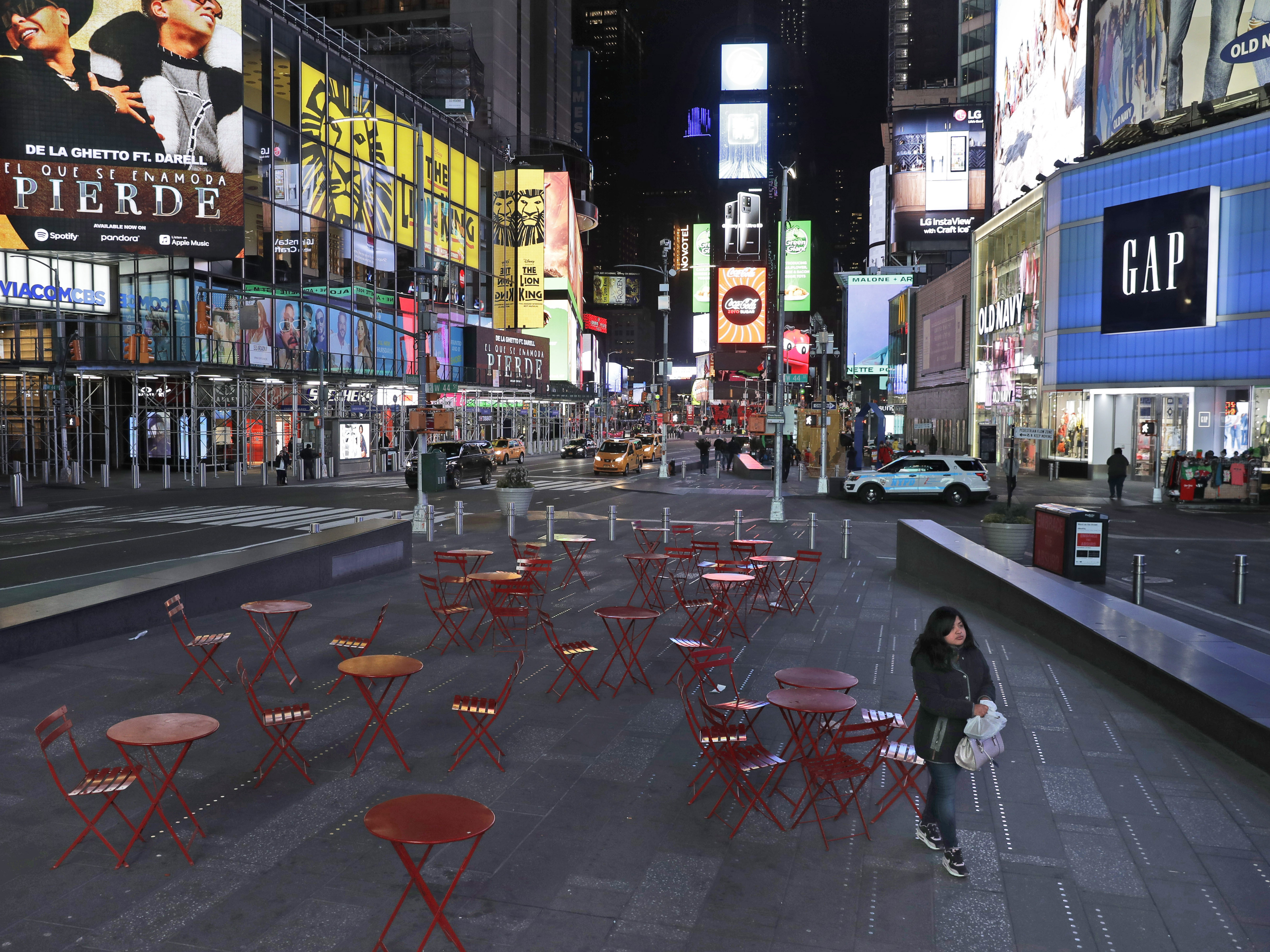 caption: A woman walks through a nearly deserted Times Square in New York Monday, as the city adjusts to widespread closures and restrictions on public life due to the COVID-19 respiratory disease.