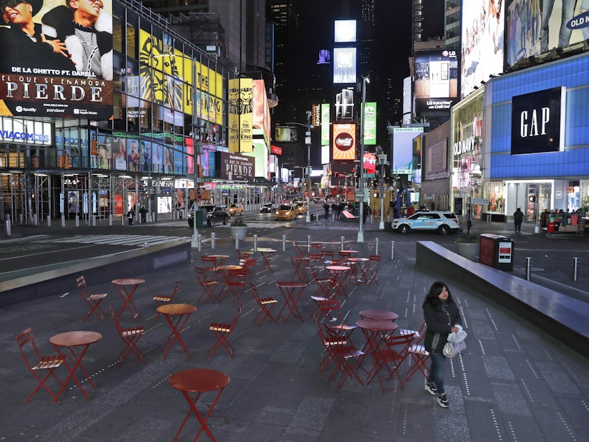 caption: A woman walks through a nearly deserted Times Square in New York Monday, as the city adjusts to widespread closures and restrictions on public life due to the COVID-19 respiratory disease.