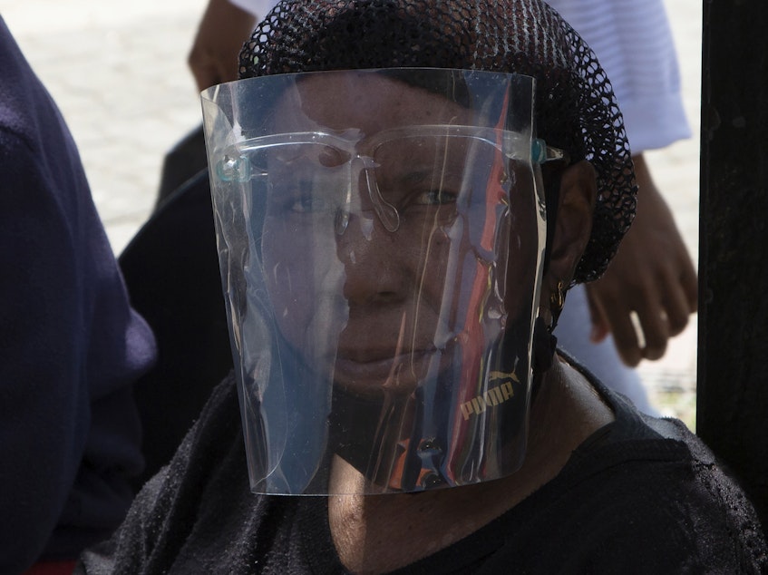 caption: A woman wears a face shield to protect against COVID-19 at a taxi rank in Soweto, South Africa, Tuesday, April 5, 2022. South Africa is seeing a rapid surge of COVID-19 cases from a sub-variant of omicron, say health experts.