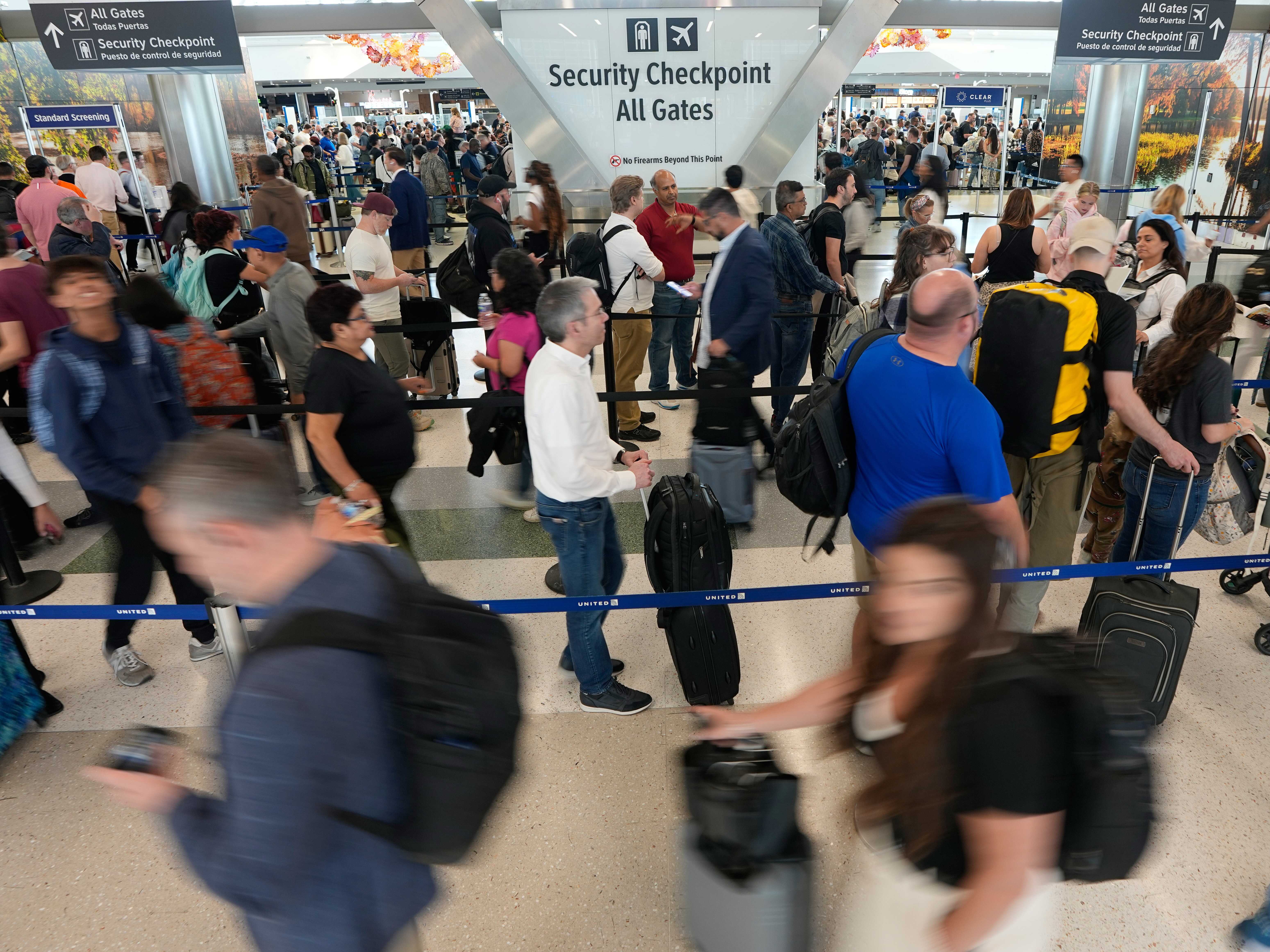 caption: Travelers wait in long security checkpoint lines at George Bush Intercontinental Airport Friday, March 27, 2026, in Houston.