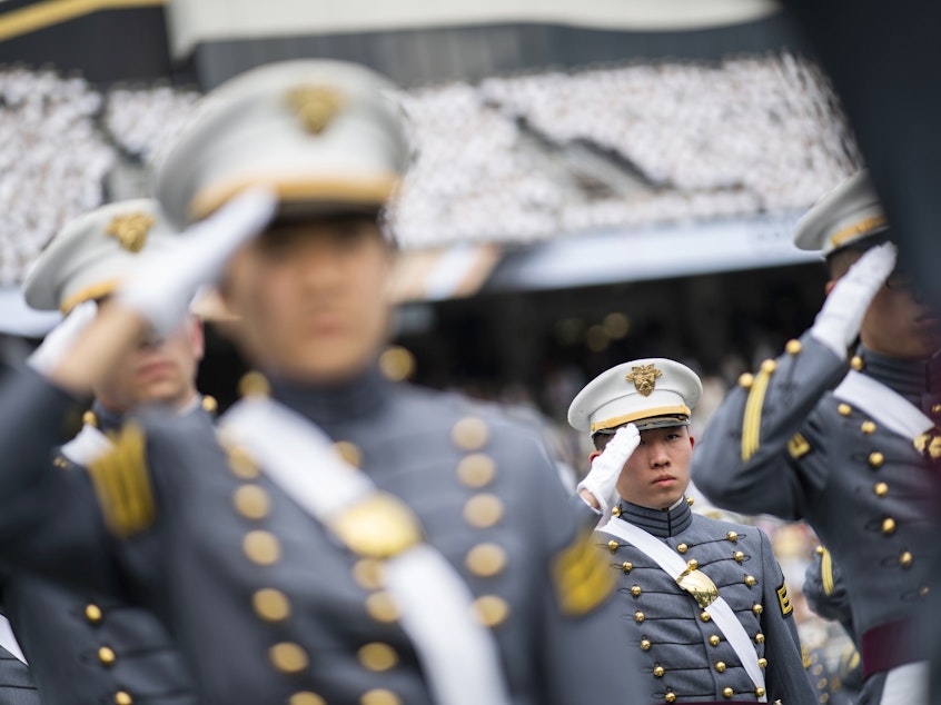 caption: Cadets salute during the graduation ceremony at the U.S. Military Academy in 2021. A change to West Point's mission statement has sparked outrage among some conservatives online.