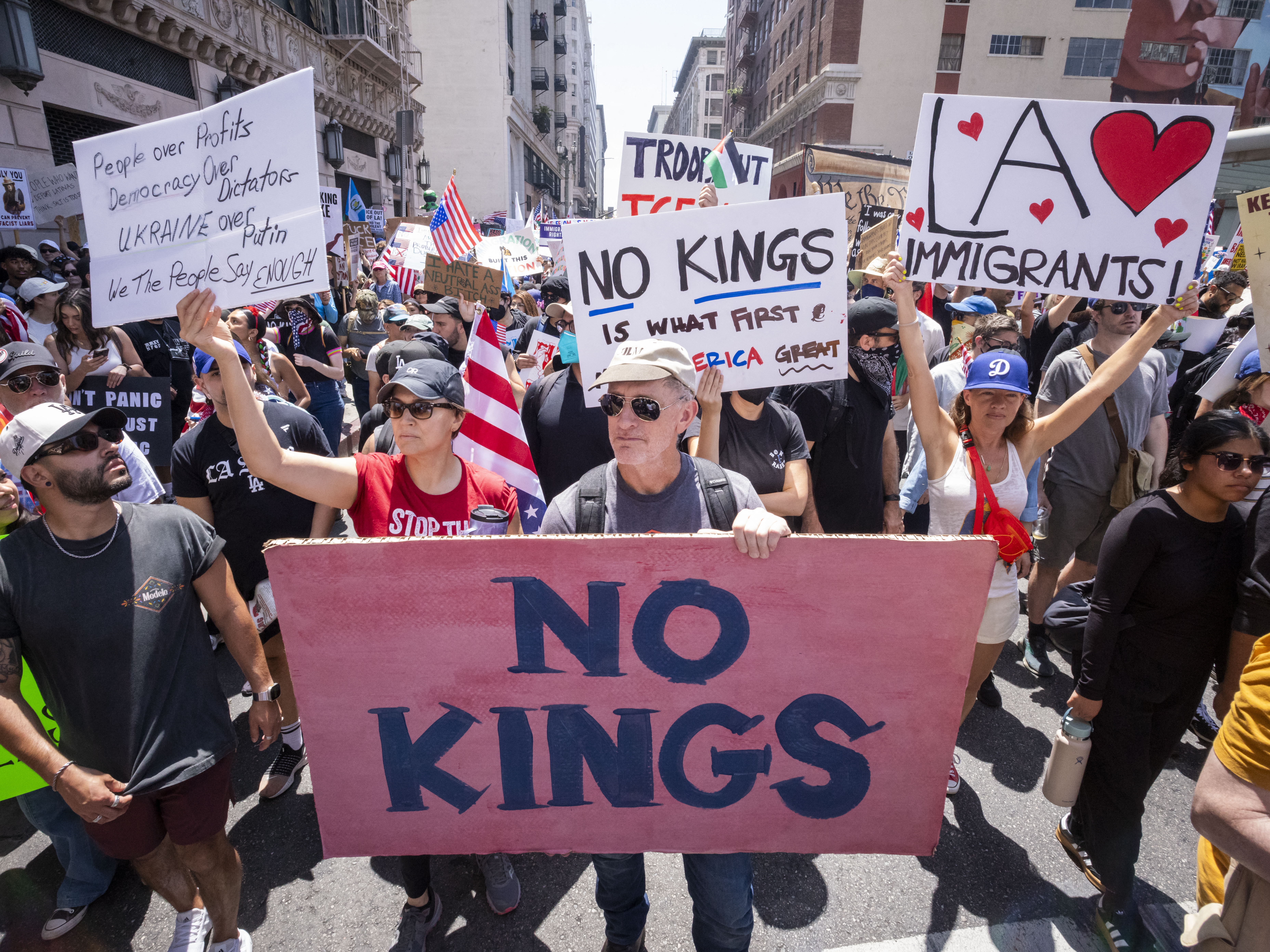 caption: Demonstrators take part in a protest against the Trump administration during the "No Kings" national rally in downtown Los Angeles on June 14, 2025, on the same day as President Trump's military parade in Washington, D.C.
