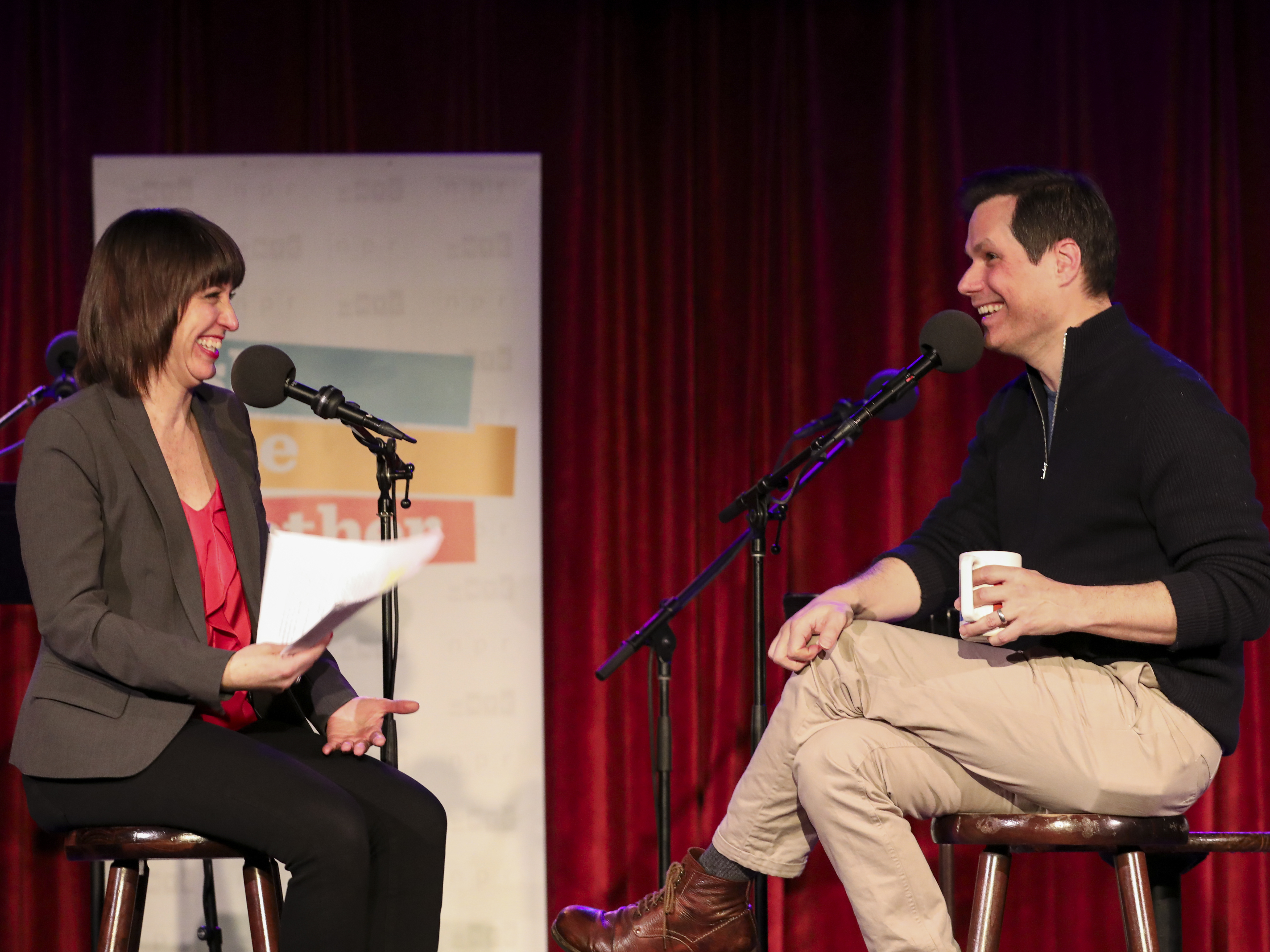 caption: Ophira Eisenberg talks with comedian Michael Ian Black on Ask Me Another at the Bell House in Brooklyn, New York.