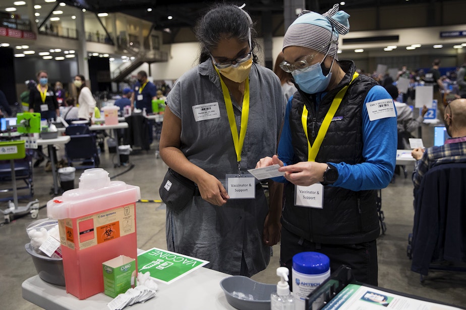 caption: Dr. Preetma Kooner, left, and registered nurse Emily Beedle, right, talk on Saturday, March 13, 2021, as the first patients arrive to be vaccinated against Covid-19 at the new civilian-led mass vaccination site at Lumen Field Event Center in Seattle.