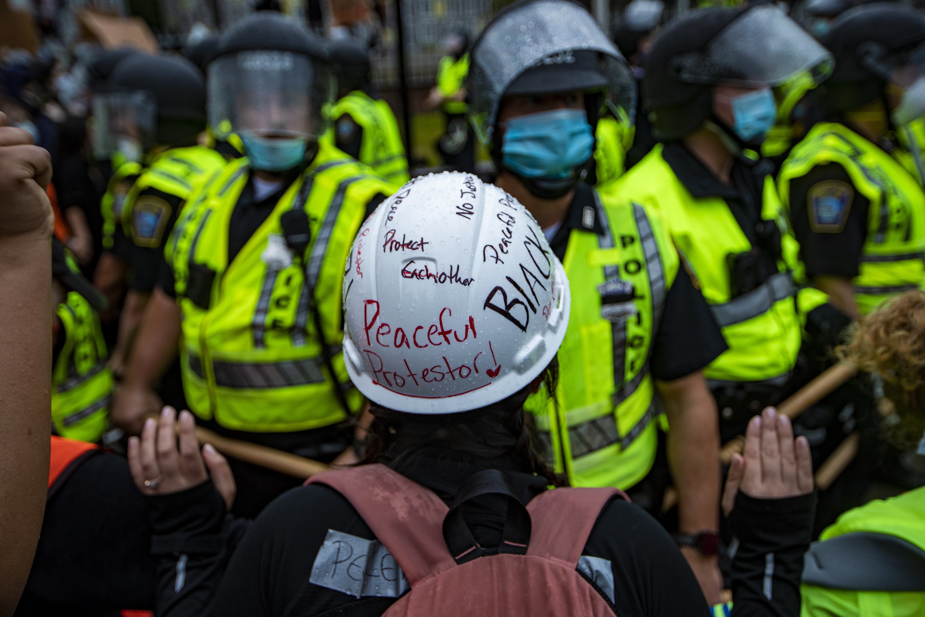 caption: A protester confronts Boston Police with hands in the air in front of Forest Hills Station in Jamaica Plain. (Jesse Costa/WBUR)