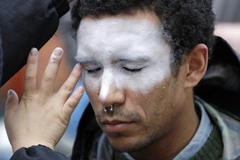 caption: In this Oct. 31 photo, a man has his face painted to represent efforts to defeat facial recognition. It was during a protest at Amazon headquarters over the company's facial recognition system.