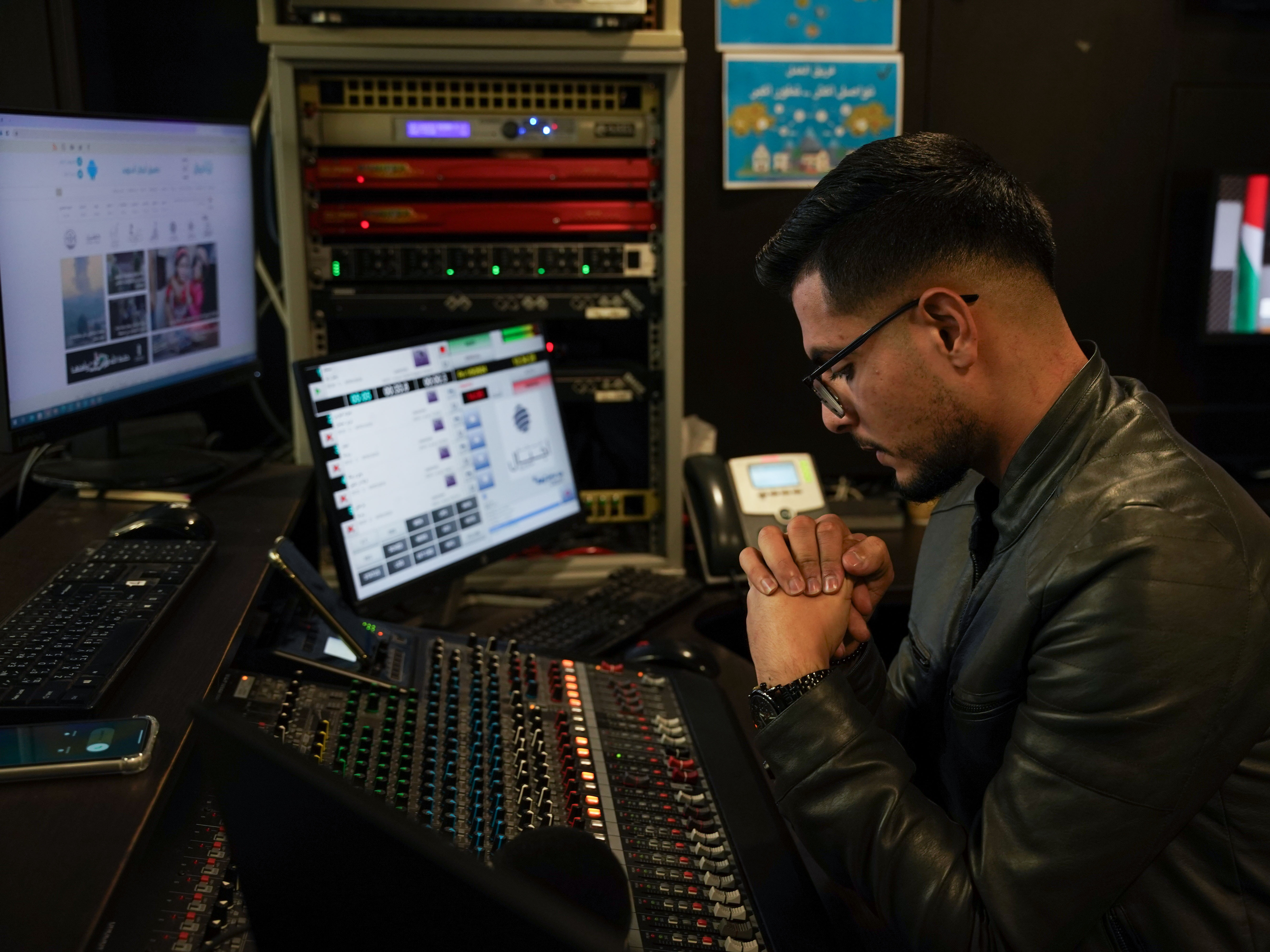 caption: Radio Ajyal producer Mohammed Daher listens to a caller during a weekly radio program in which Palestinians send messages to their relatives in Israeli prisons.