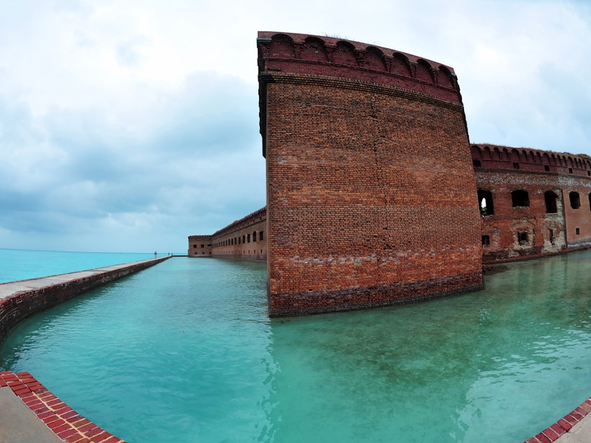 caption: Over the holiday weekend, hundreds of migrants landed in Dry Tortugas National Park, about 70 miles west of Key West, Fla., in the Gulf of Mexico. Tourists walk along the sea wall surrounding Fort Jefferson in the park in February 2016.