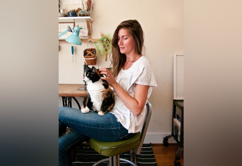 caption: Jess Marie with her cat Moneypenny. For young adults like Marie, affordability is big issue when shopping for health plans. 