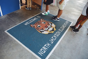 caption: Students wait in line to check in for the first day of school at North Jackson Elementary. As they walk in, they are greeted by their school mascot, the tiger.