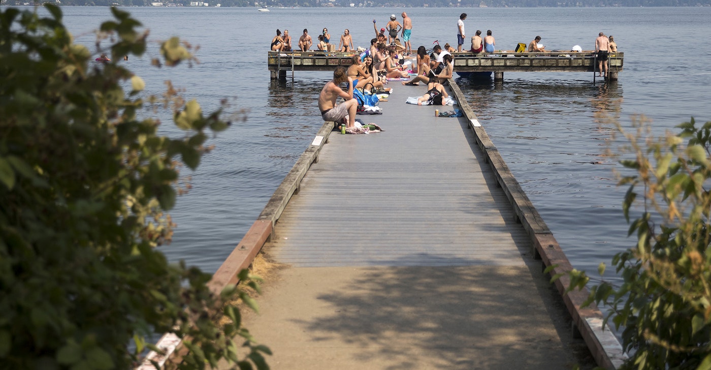 caption: A crowd gathers on a public dock on Monday, July 30, 2018, near Madrona Park in Seattle. 