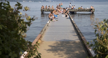 caption: A crowd gathers on a public dock on Monday, July 30, 2018, near Madrona Park in Seattle. 