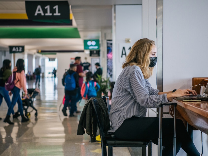caption: The CEOs of the major U.S. airlines have called on President Biden to end the federal mask mandate for public transportation. Here, a traveler works on a laptop computer at George Bush Intercontinental Airport in Houston on Dec. 3.