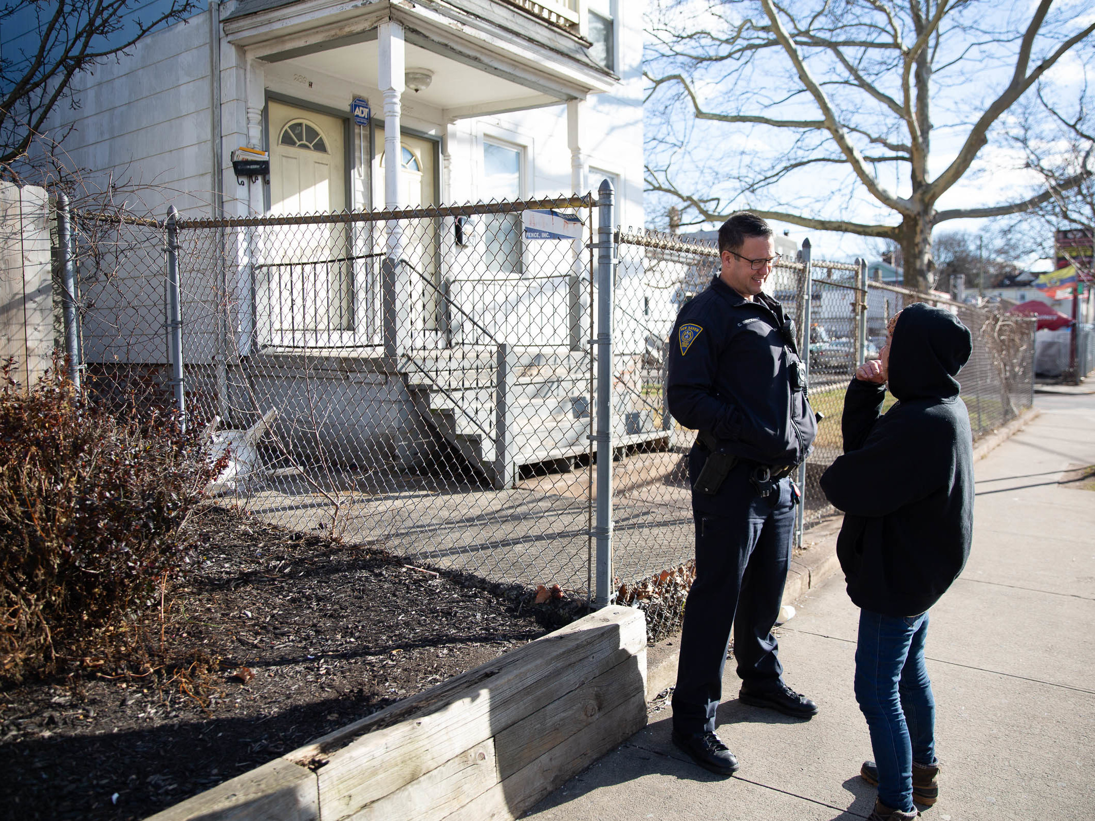 caption: Officer Christian Bruckhart checks in with a resident of New Haven's Fair Haven neighborhood. Community building is a priority for many younger officers.