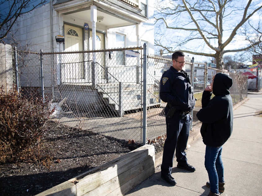 caption: Officer Christian Bruckhart checks in with a resident of New Haven's Fair Haven neighborhood. Community building is a priority for many younger officers.