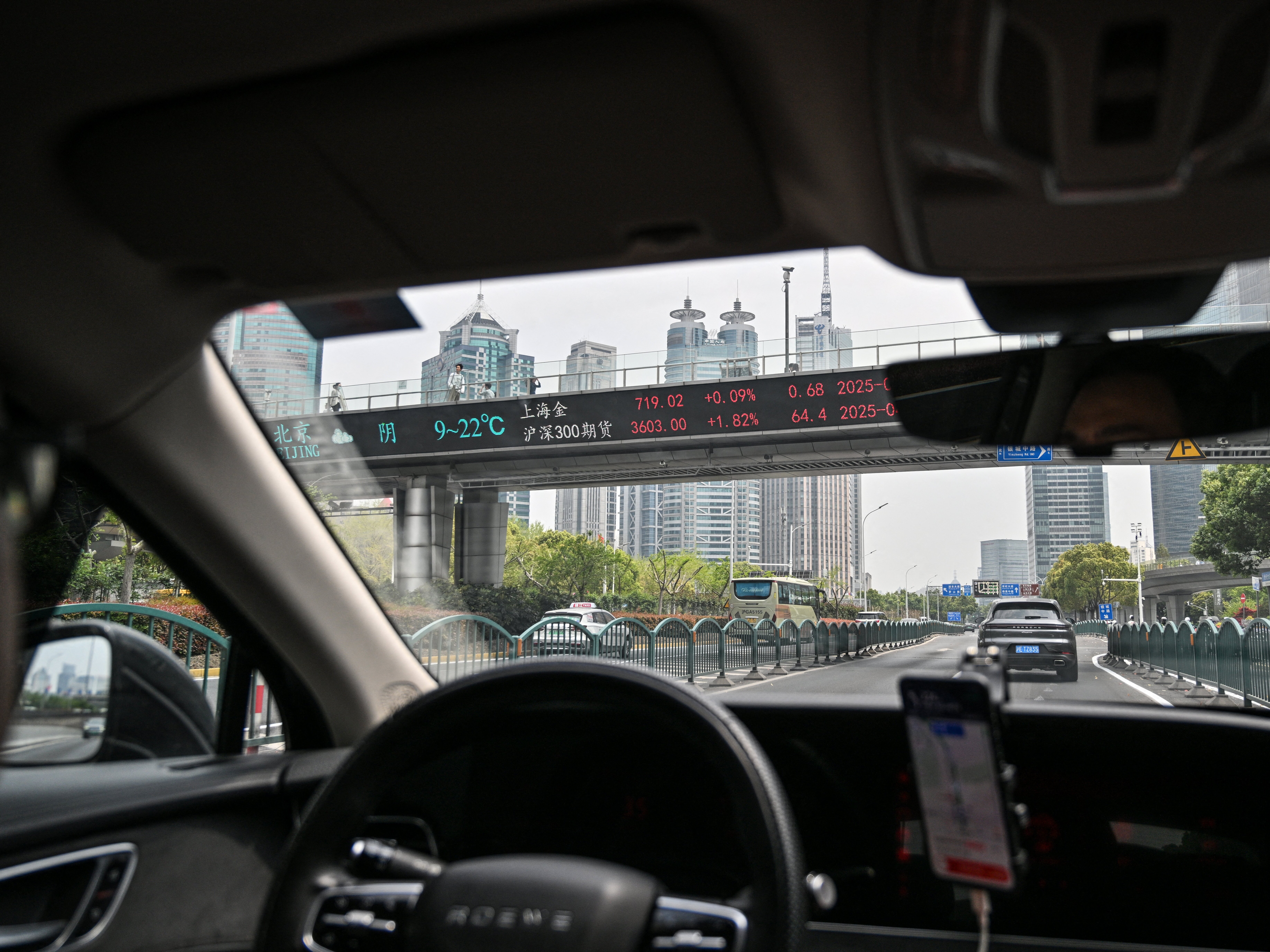 caption: A DiDi ride-hailing driver travels through the financial district in Shanghai on April 9.