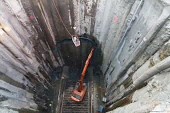 caption:  Crews chip away a circle on the southern wall of the pit that was built to access and repair Bertha, the SR 99 tunneling machine. Eventually it helped Bertha break through/