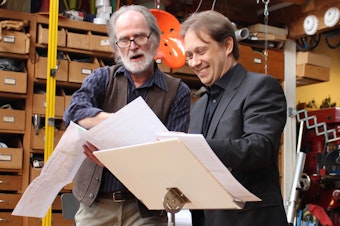 caption: The artist Trimpin and Seattle Symphony conductor Ludovic Morlot look over Trimpin's plans.